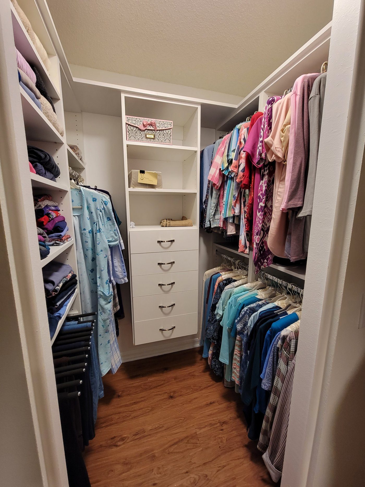 Walk-in closet with colorful folded clothing by Create More Space