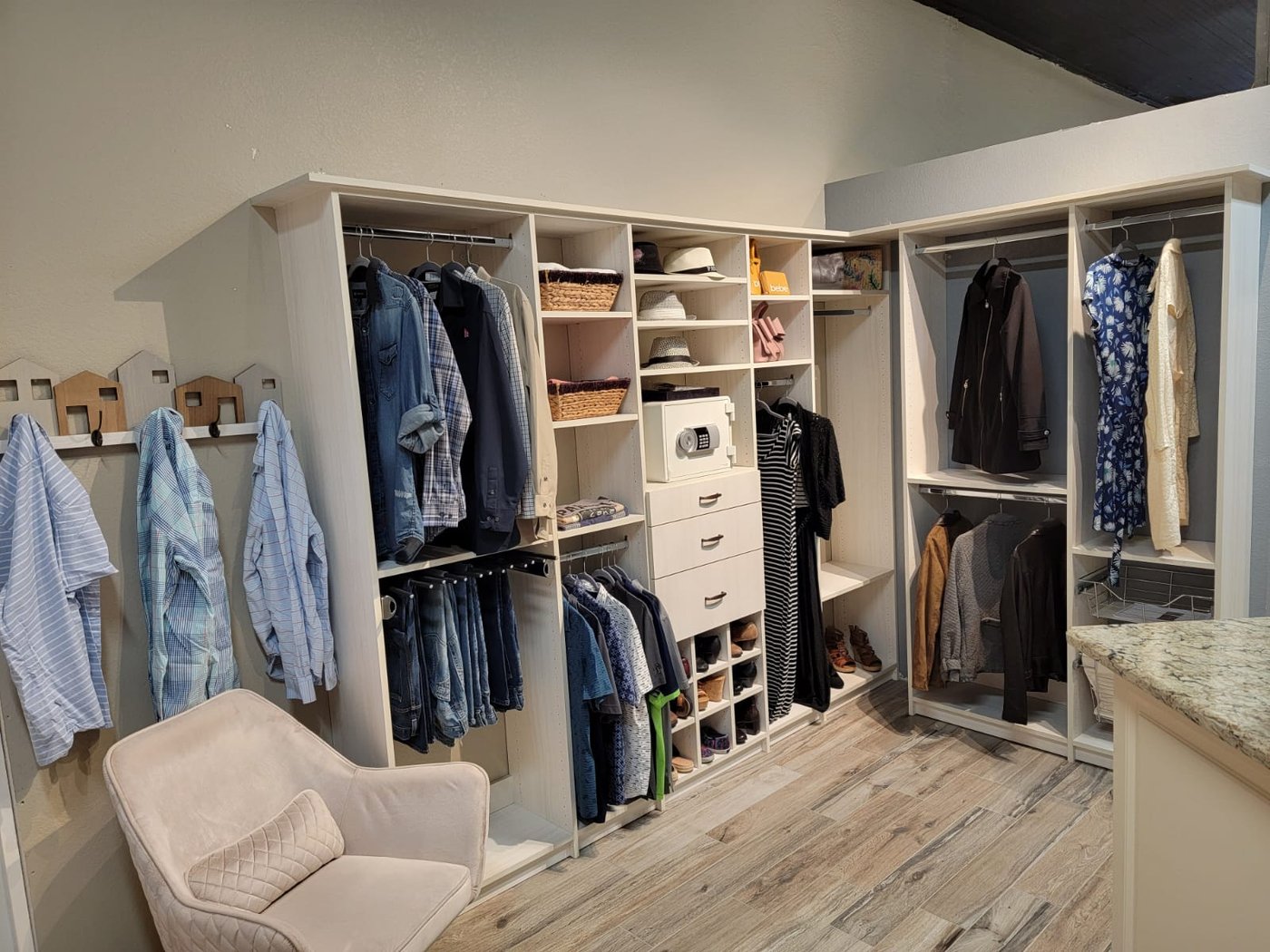 Walk-in closet with hanging jackets, island and seating by Create More Space